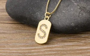 Gold initial S pendant necklace detail view, dazzling zircon gemstone inlay on metal tag.