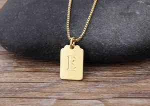 Dettaglio collana con ciondolo lettera placcato oro, primo piano charm quadrato lettera E.