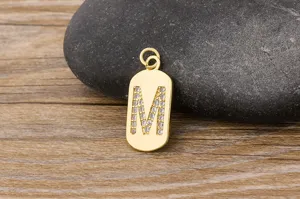 Gold letter M pendant detail, micro pave cubic zirconia initial charm, elegant jewelry close-up
