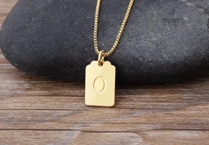 Dettaglio in primo piano della collana con ciondolo lettera O placcata oro su pietra.