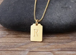 Primo piano dettaglio della collana con ciondolo quadrato lettera R placcata in oro