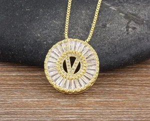 Primo piano di collana in ottone dorato con ciondolo circolare scintillante in zircone lettera V.