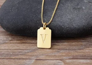 Primo piano dettaglio della collana con ciondolo quadrato minimalista con lettera V oro.