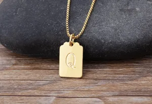 Dettaglio in primo piano della collana con ciondolo quadrato lettera Q placcato oro.