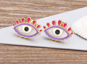 Close-up detail of creative evil eye stud earrings with colorful enamel and gold plating.