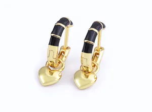 Close-up detail of chic gold-plated hoop earrings featuring black enamel segments and cute heart pendants.