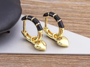 Gold hoop earrings with black enamel segments and hanging heart pendant, detailed close up view.