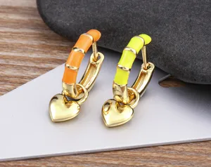 Close-up detail of colorful enamel hoop earrings with gold-plated heart charms and cute design.