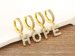 Close-up detail of gold-plated hoop earrings featuring sparkling cubic zirconia letter charms spelling HOPE.