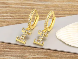 Detailed view of gold plated micro pave zircon letter pendant hoop earrings, shiny close-up.
