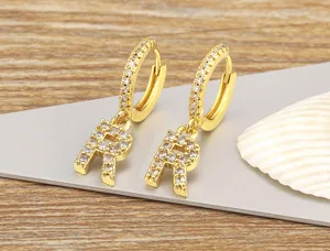 Close-up detail of gold 18k plated copper hoop earrings with sparkling micro zircon letter R pendant.