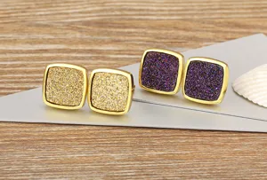 Detail shot of vintage square mineral stud earrings featuring sparkling gold and purple textures.