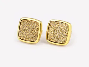Close up detail view of vintage style gold square glitter stone stud earrings texture.