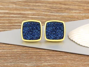 Square blue stone stud earrings detail close up view, vintage gold edge metallic design.