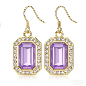 Primo piano dettaglio orecchini pendenti cristallo viola rettangolare bordo strass oro.