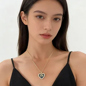 Model wearing a dainty gold heart pendant necklace with pearl border and bow detail.