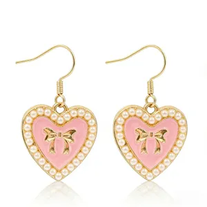 Gold drop earrings featuring a pink heart, pearl border, and a cute bow detail close-up.