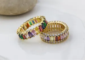 Primer plano detallado de anillos de eternidad de circonita baguette colorida.