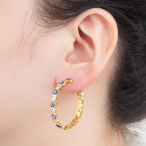 Detail shot of gold plated evil eye hoop earrings with sparkling zirconia crystals on ear.