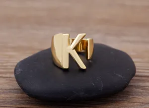 Close up view of stylish gold letter K open ring showcased on a dark stone surface.