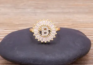 Close-up detail of gold-plated letter B ring with sparkling cubic zirconia on stone.