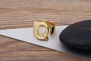 Close-up detail of the gold-plated letter Q ring, showing the polished open metal band design.