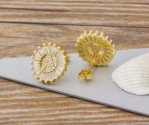 Pendientes de tuerca con letra A chapados en oro y circonitas cúbicas en primer plano.