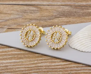 Primer plano detalle de pendientes letra H de circonita, joyería de cobre chapado oro.