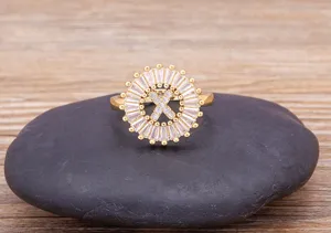 Detailed close-up of a gold-plated letter X zircon ring resting on a smooth dark stone.