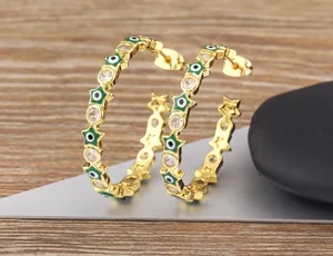 Close-up view of gold-plated pentagram evil eye hoop earrings with sparkling cubic zirconia.