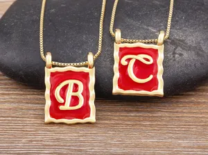 Gold-plated square letter B and C necklace detail featuring red enamel drip oil design.