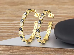 Close-up detail of 18k gold plated evil eye hoop earrings with sparkling zirconia and star charms.