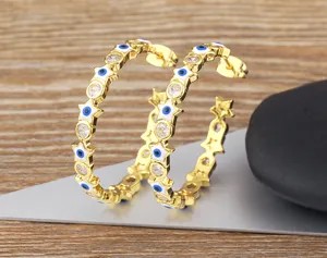 Detailed view of gold evil eye hoop earrings with sparkling cubic zirconia crystals.