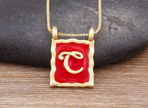 Close-up detail of the red enamel square letter pendant necklace, elegant gold finish.