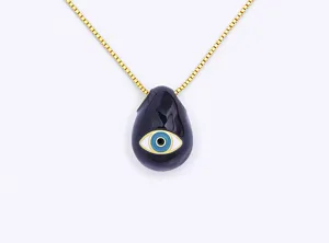 Close-up detail of the black teardrop evil eye pendant and gold chain necklace showcasing enamel.