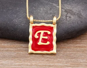 Close-up detail of the red enamel square letter E pendant necklace with gold chain.