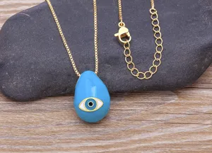 Close-up detail of the 18k gold plated evil eye pendant necklace on a stone and wood background.