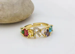 Primo piano dettagliato di anello in zircone colorato dorato con lettera R e pietre vive.