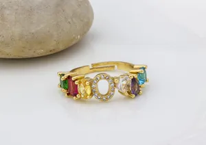 Dettaglio dell'anello con lettera O placcato oro e zirconi colorati, gioiello regolabile.