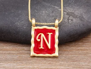 Close-up detail of the gold-plated letter N square pendant necklace with red enamel.