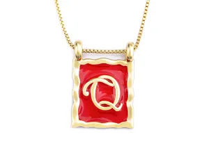 Gold-plated square pendant necklace detail showing red enamel and letter Q charm.