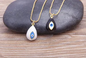 Gold plated evil eye pendant necklace detail view showing black and white enamel teardrop charms.