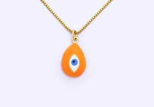 Gold plated evil eye pendant necklace detail shot, orange teardrop enamel charm close up view.