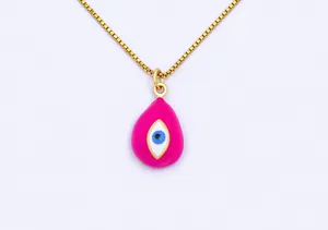 Detail shot of a gold-plated necklace featuring a vibrant pink enamel teardrop evil eye pendant.