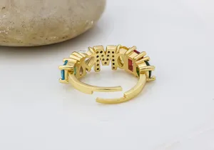 Primo piano dettagliato dell'anello con lettere in oro 18K e pietre di zircone colorate.