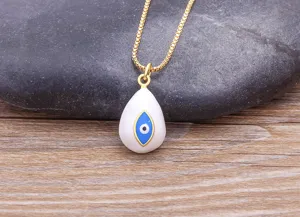 Detail view of a gold-plated evil eye pendant necklace with white enamel drop design.
