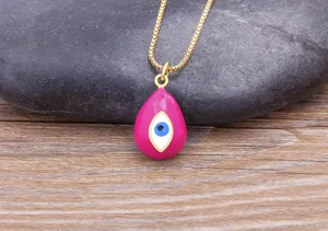 Close-up detail of hot pink enamel evil eye pendant necklace with gold box chain.