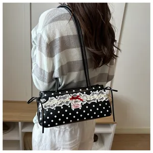 Detailed view of a chic black polka dot shoulder bag featuring delicate white lace trim and red bow.