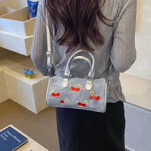 Detailed view of a stylish silver boston shoulder bag featuring charming red cherry embroidery.