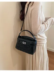 Detailed view of a chic black crossbody bag with embossed heart pattern and metal lock closure.